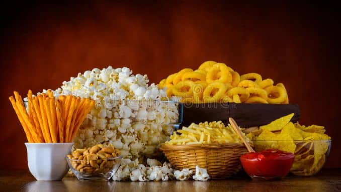unhealthy-junk-food-different-types-popcorn-salty-sticks-salty-crackers-wooden-table-still-life 
