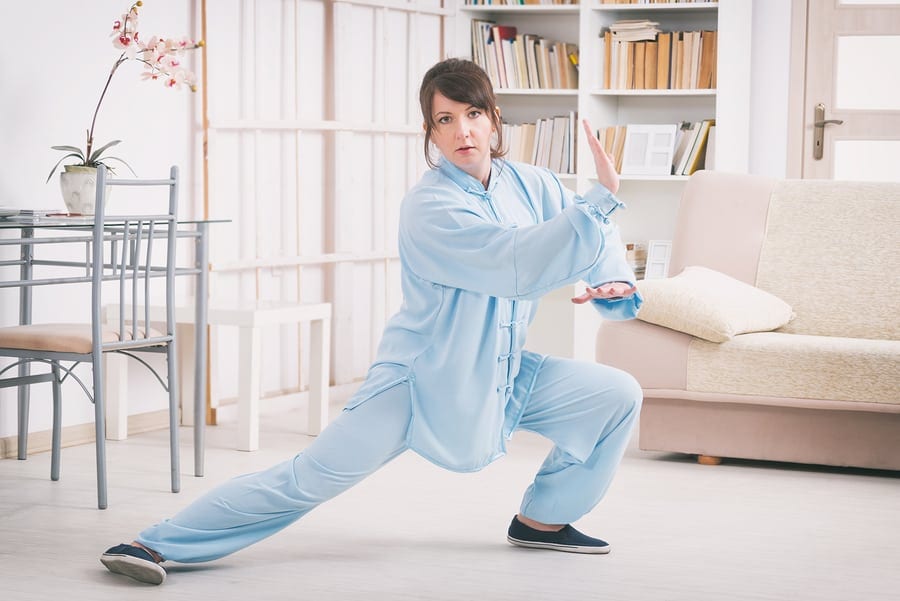 Beautiful woman doing qi gong tai chi exercise or reiki wearing professional, original Chinese clothes at home
