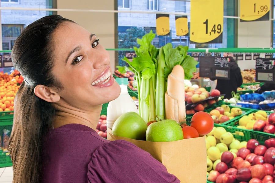 Young woman holding a grocery bag full of fresh and healthy food