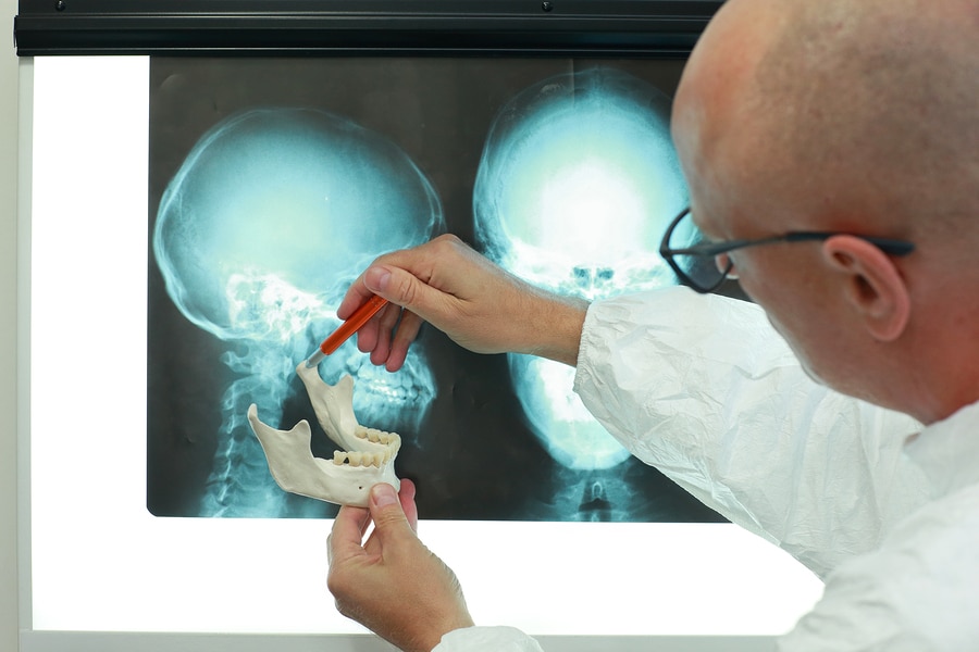 Professional with model of lower jaw watching images of skull  a