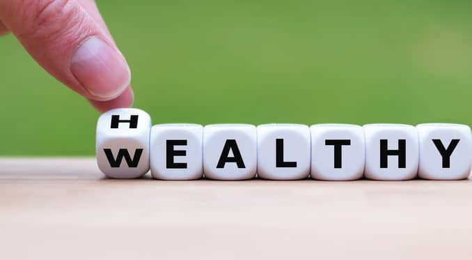 Hand turns a dice and changes the expression "WEALTHY" to "HEALT
