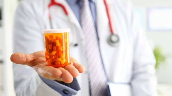 doctor hand holding and offering to patient jar of pills