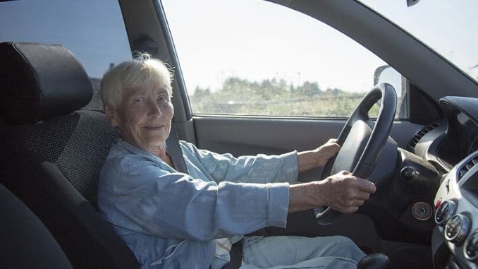 an smiling elderly woman driving car