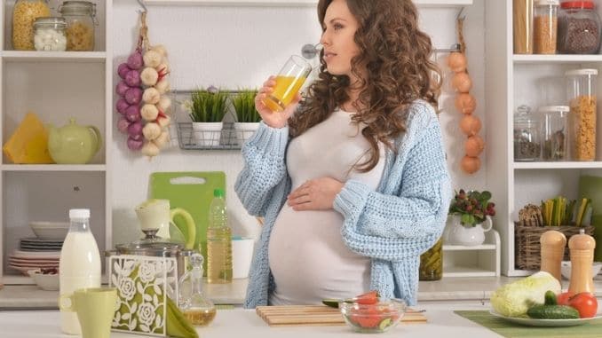 Pregnant young woman having breakfast