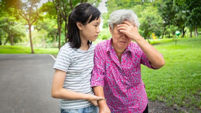 asian senior grandmother has headache touching her head